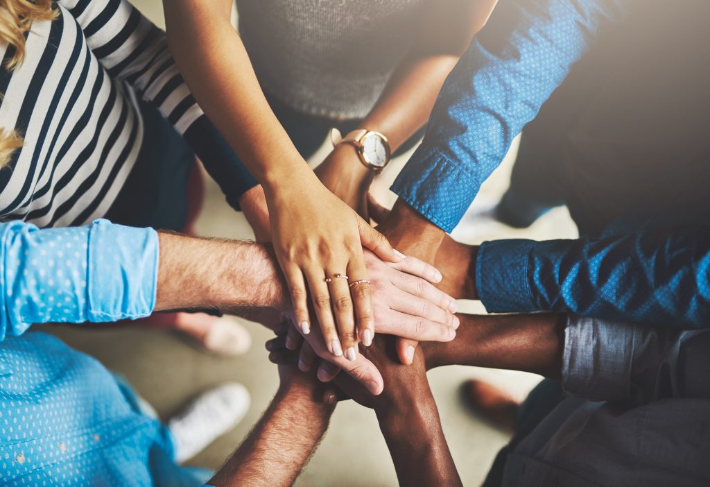 Shot of a group of creative businesspeople standing with their hands in a huddle.